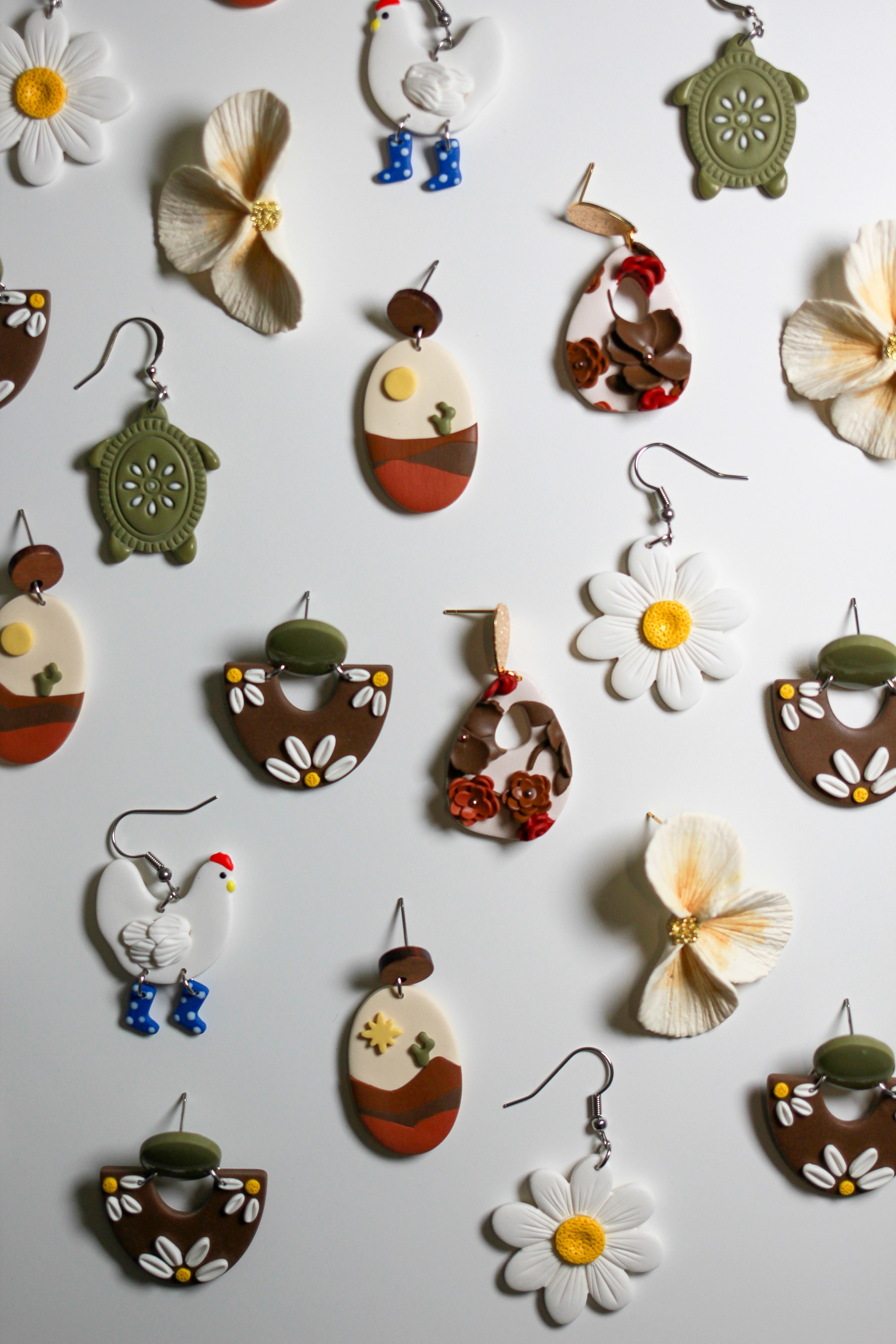 Multiple pairs of whimsy earrings on a white surface. 