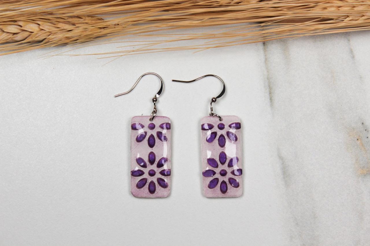 Pair of purple floral earrings on a light gray background
