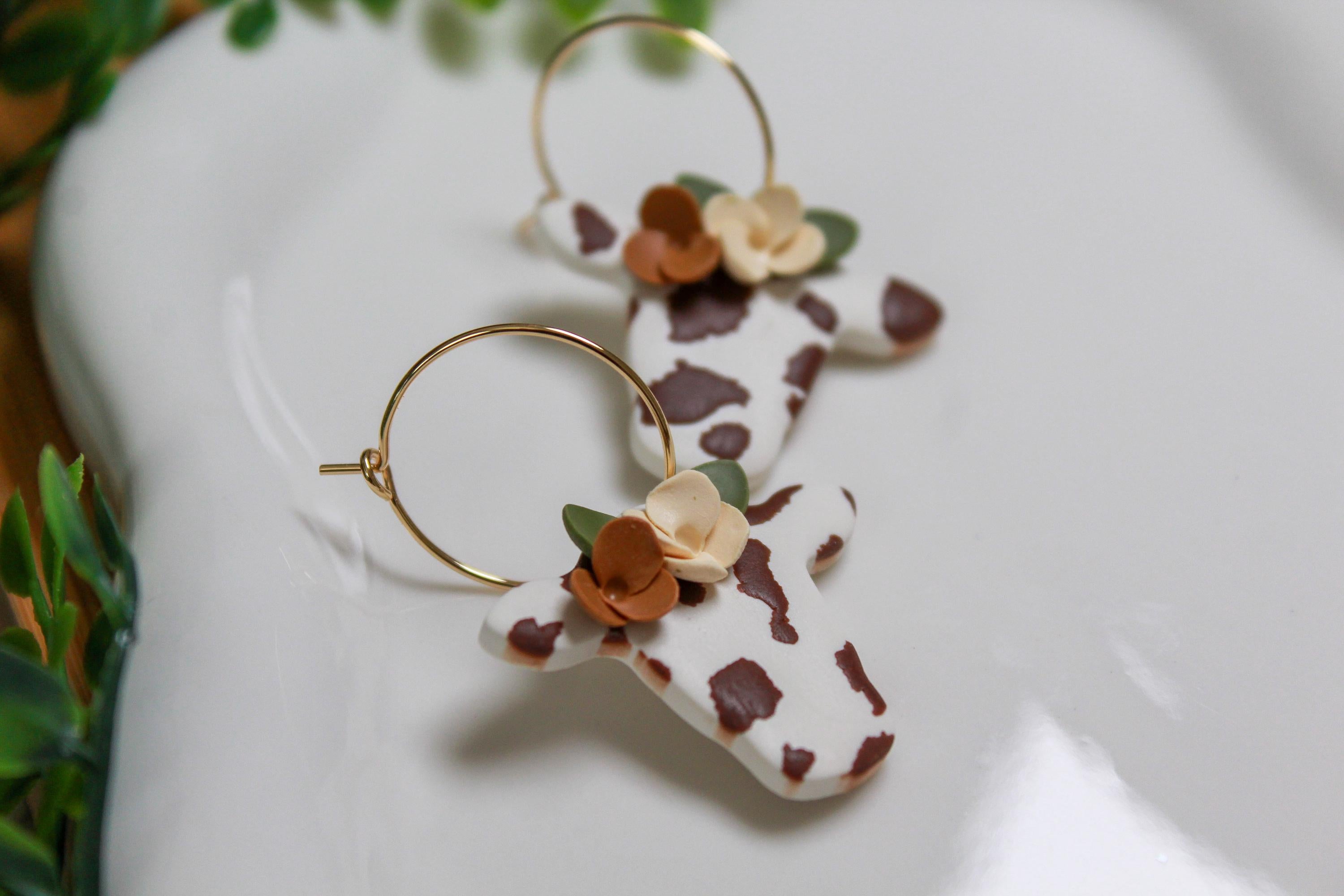 Pair of cow earrings with floral designs on a white surface