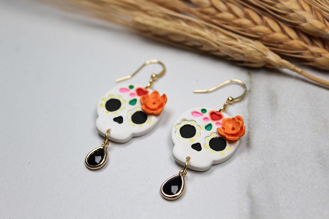 Pair of skull-shaped earrings with floral details on a light background