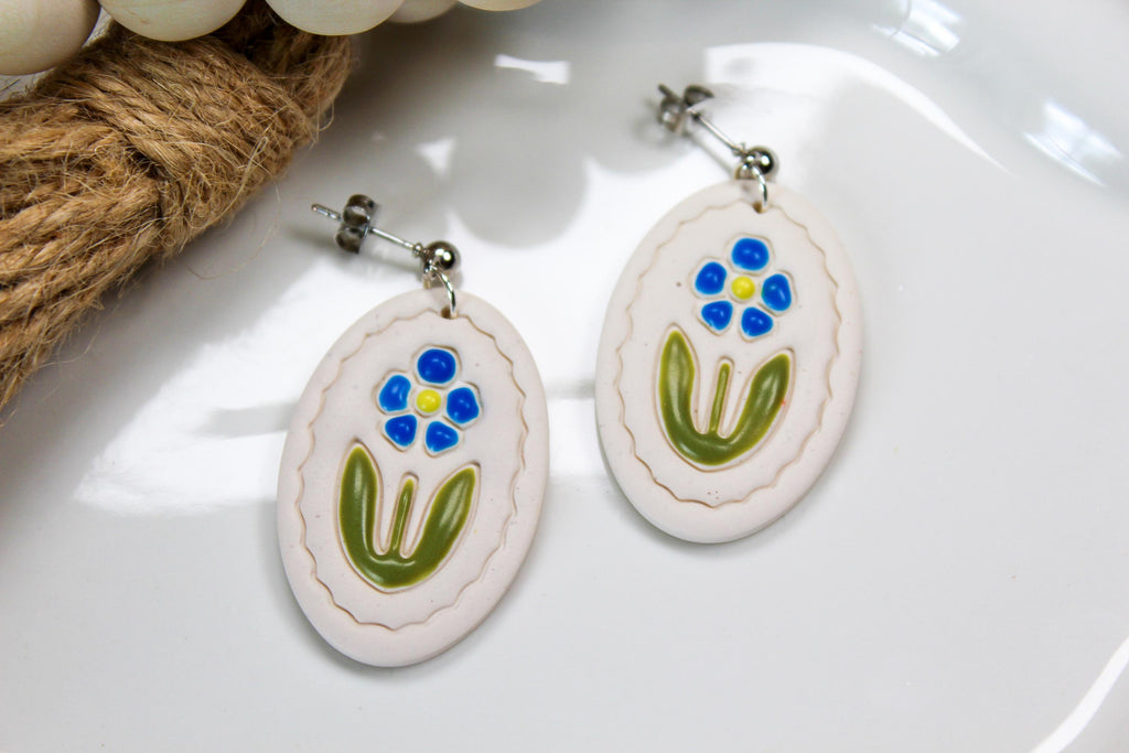 Oval-shaped earrings with floral design on a white surface