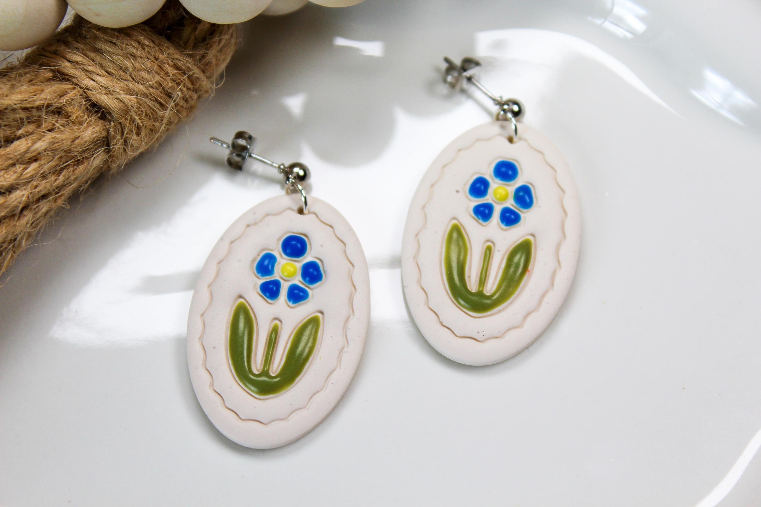 Oval-shaped earrings with floral design on a white surface