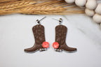Cowboy boot earrings with pink flowers on a light background
