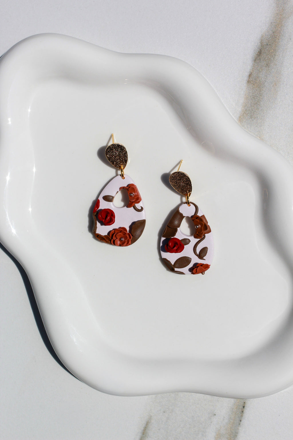 Pair of earrings with floral design on a white dish