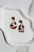 Pair of earrings with floral design on a white dish