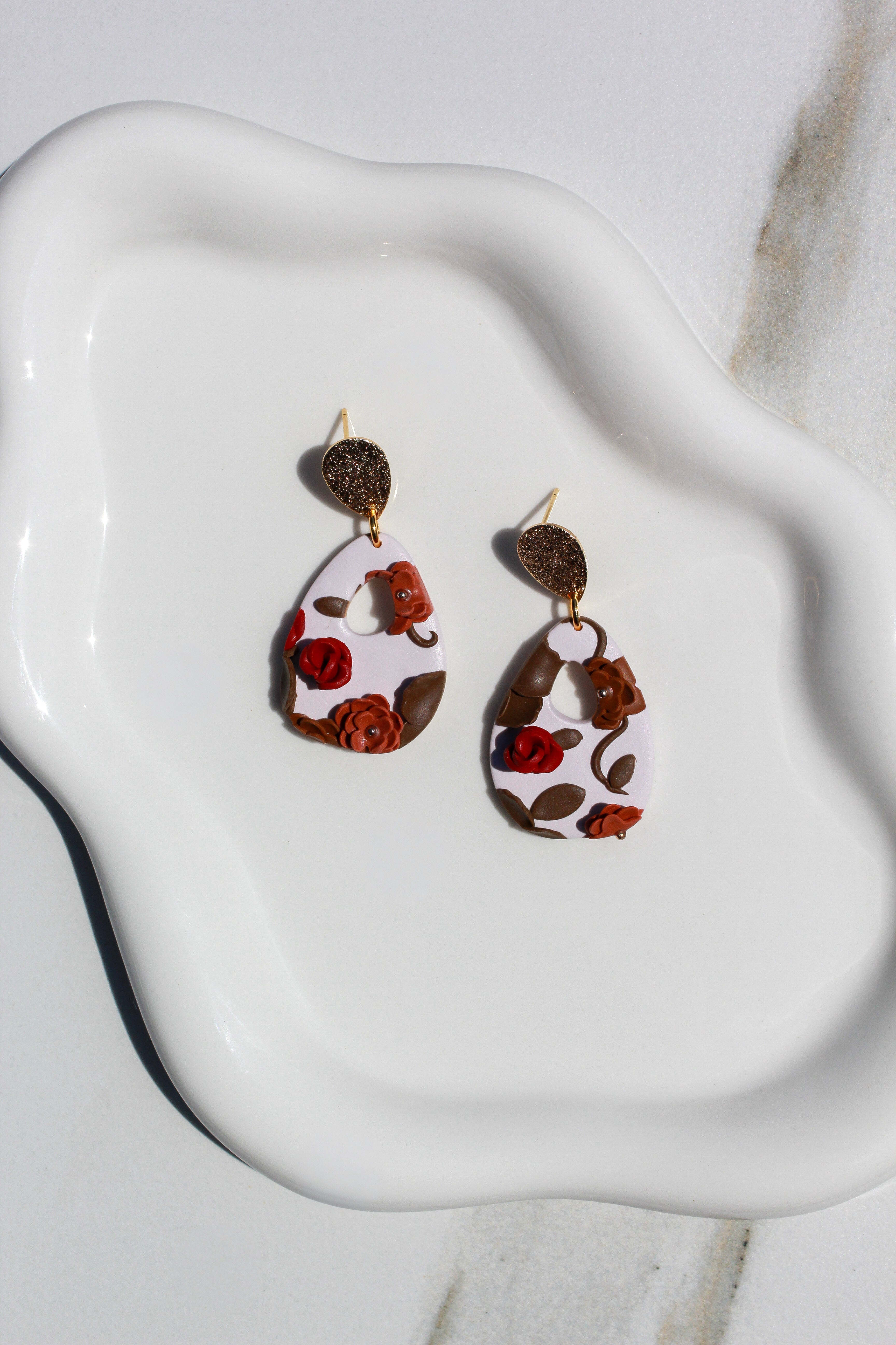 Pair of earrings with floral design on a white dish