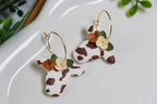 Cow head hoop earrings with floral accents on a white surface