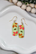 Colorful oval-shaped earrings on a white dish with wooden beads in the background
