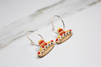Sombrero-shaped earrings on a light wooden surface