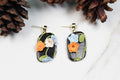 Floral earrings on a white background with pine cones.