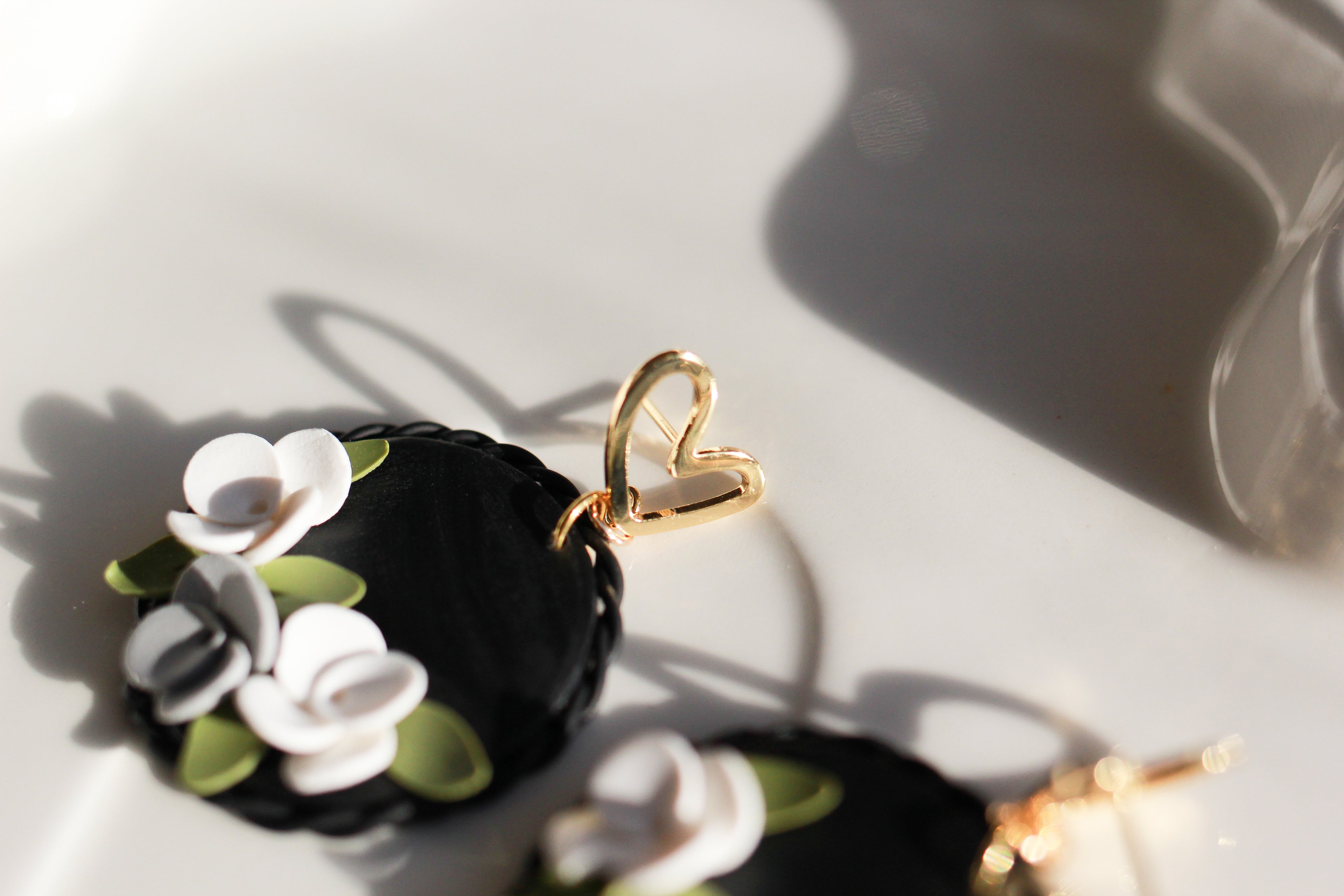 Black earring with white flowers on a light gray background