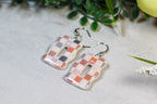 Pair of earrings with a checkered design on a light background