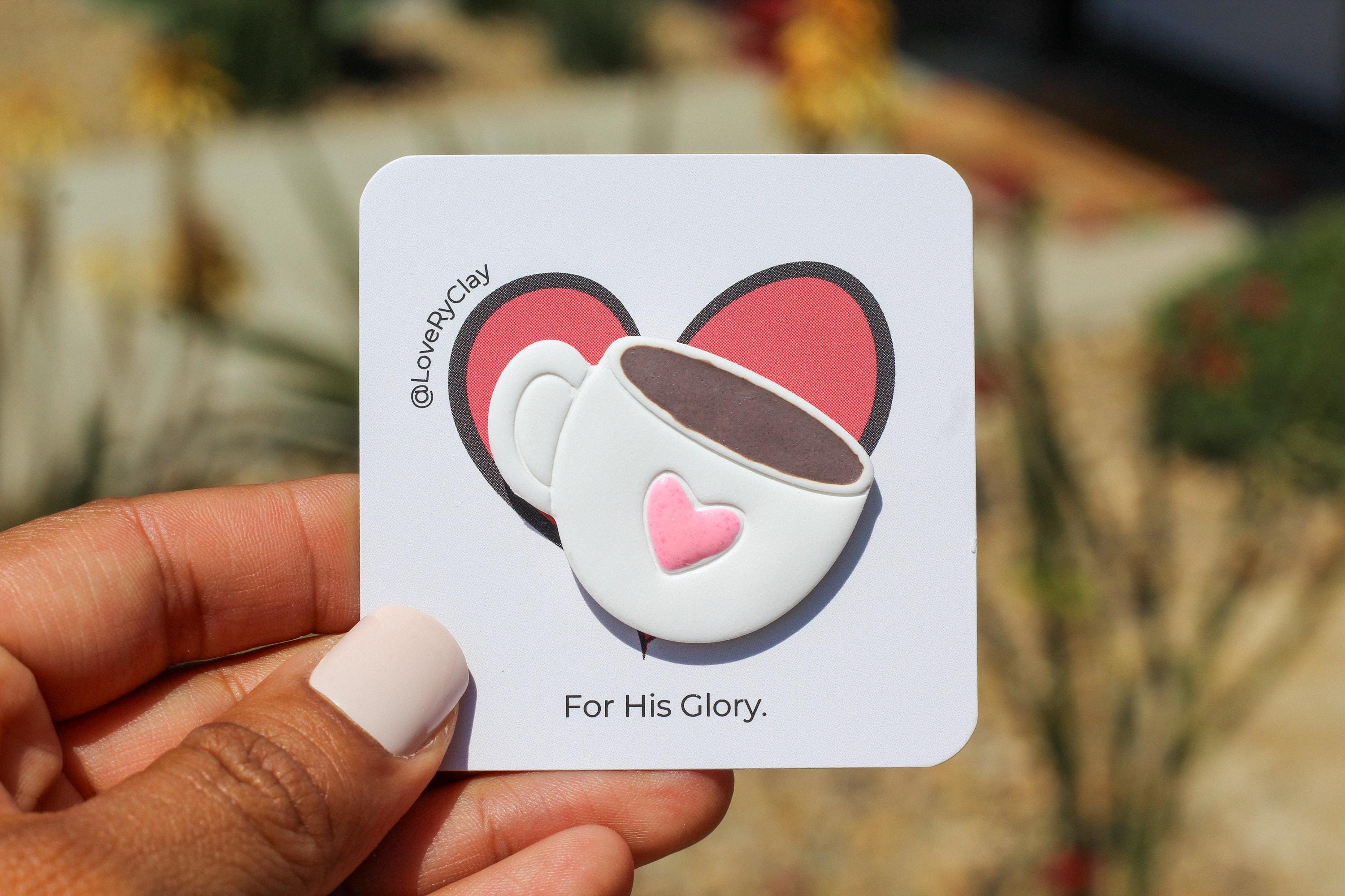 Card with a coffee cup pin  held by a hand, with a blurred background.