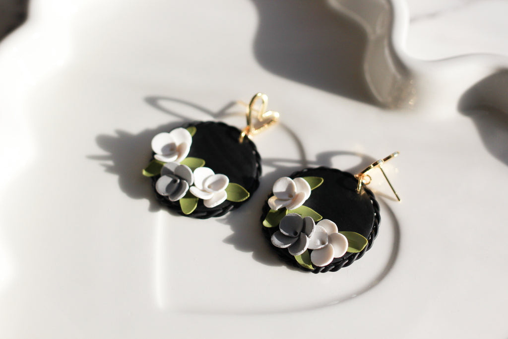 Black earrings with floral designs on a white surface