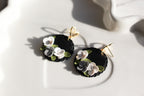 Black earrings with floral designs on a white surface