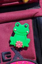 Green frog-shaped pin on a red bag