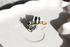 Close-up of black and white book earrings with huggie accessory on a white surface