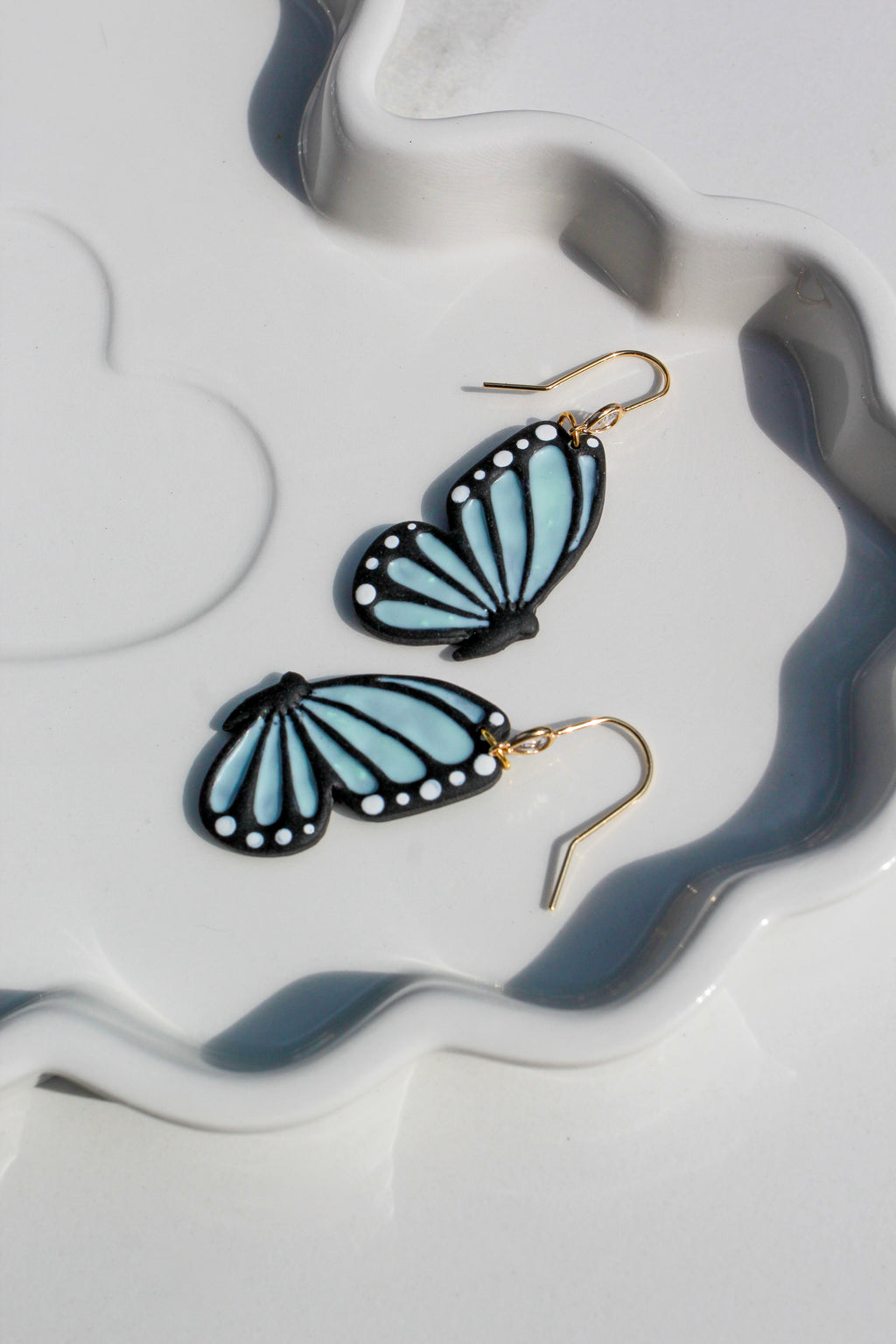 Butterfly-shaped earrings on a decorative white and gray plate