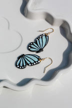 Butterfly-shaped earrings on a decorative white and gray plate