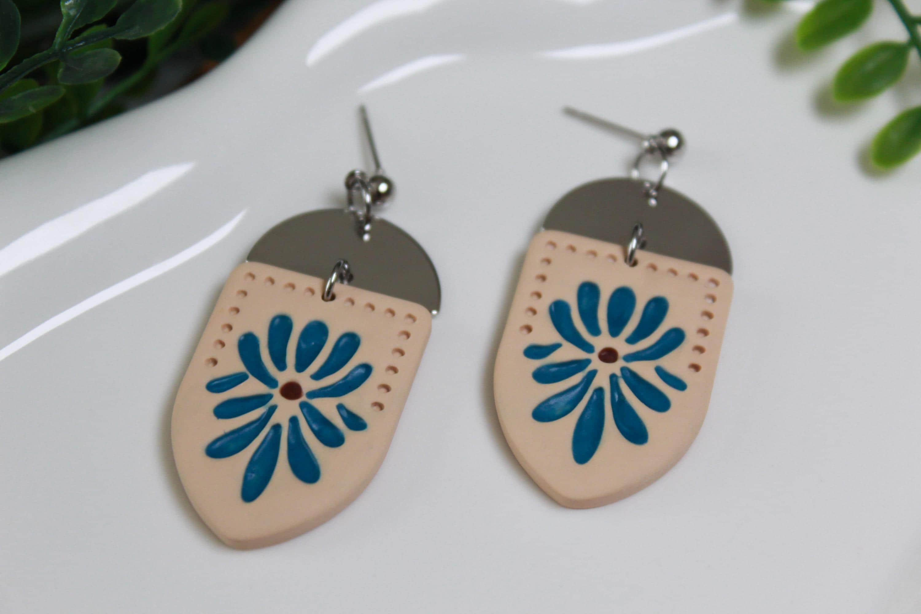 Pair of earrings with blue floral design on a white surface