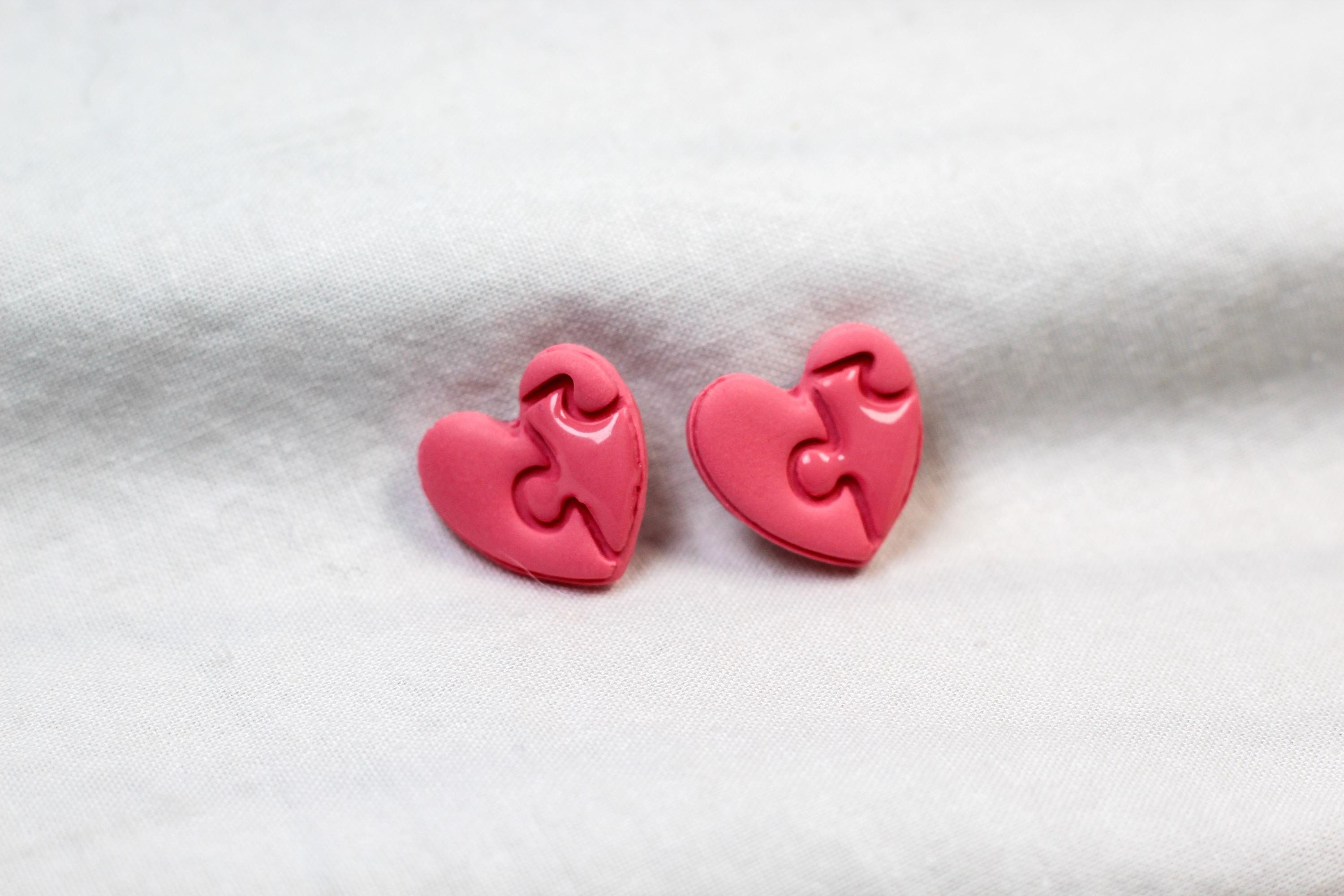 Pink heart-shaped earrings on a light gray background