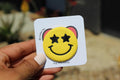 Hand holding a card with a smiley face pin