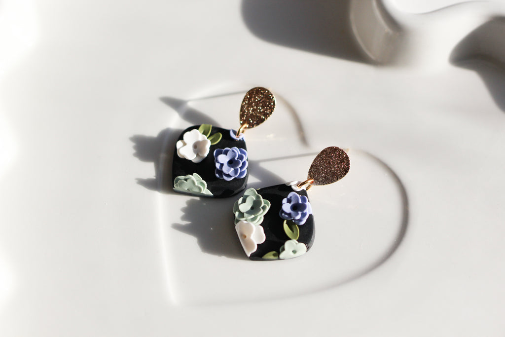 Floral earrings on a white surface with soft shadows