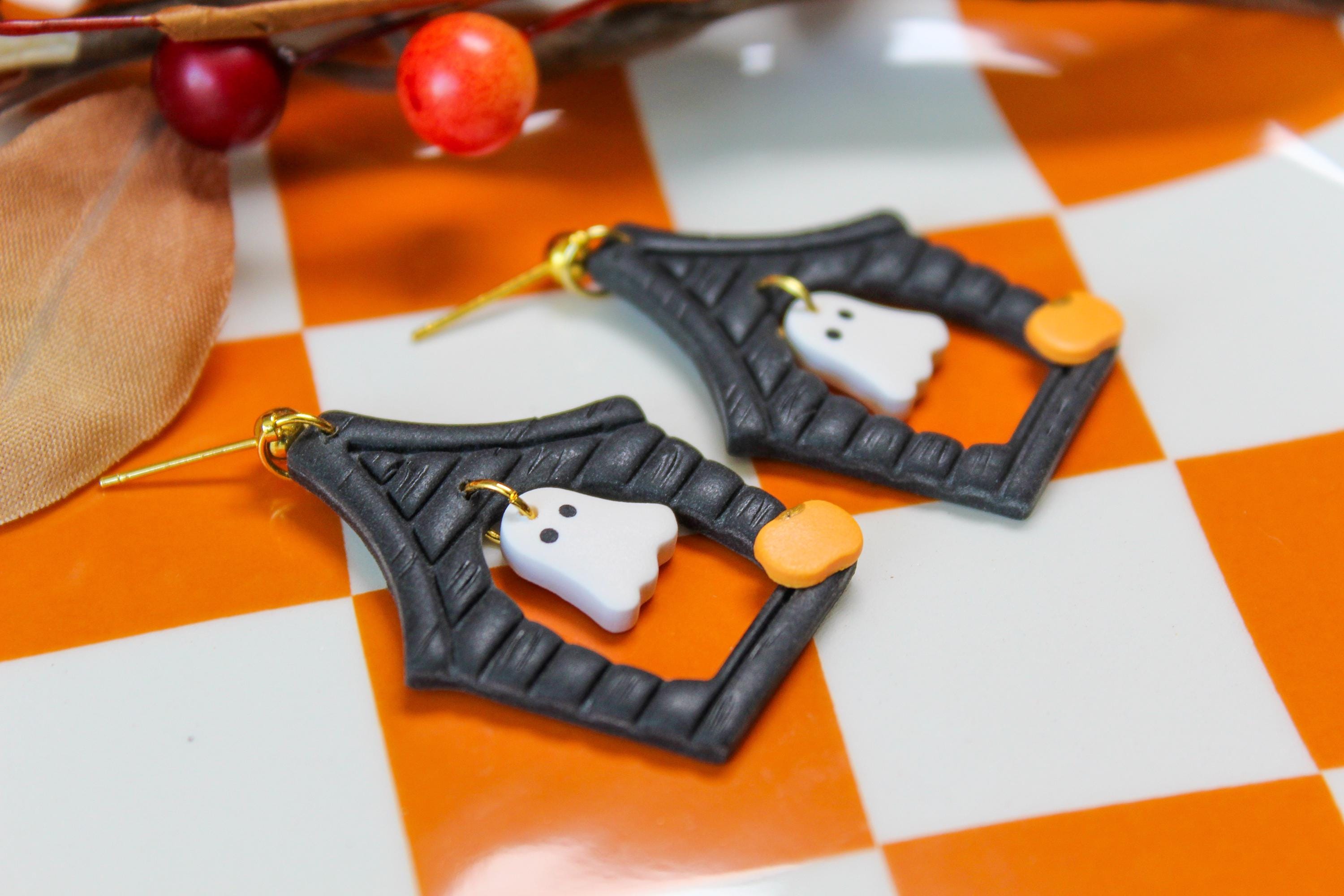 Halloween-themed haunted house earrings with ghost designs on a checkered background