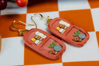 Pair of orange earrings with decorative elements on a checkered background
