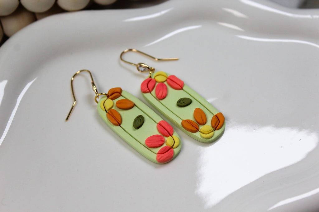 Colorful floral earrings on a white dish