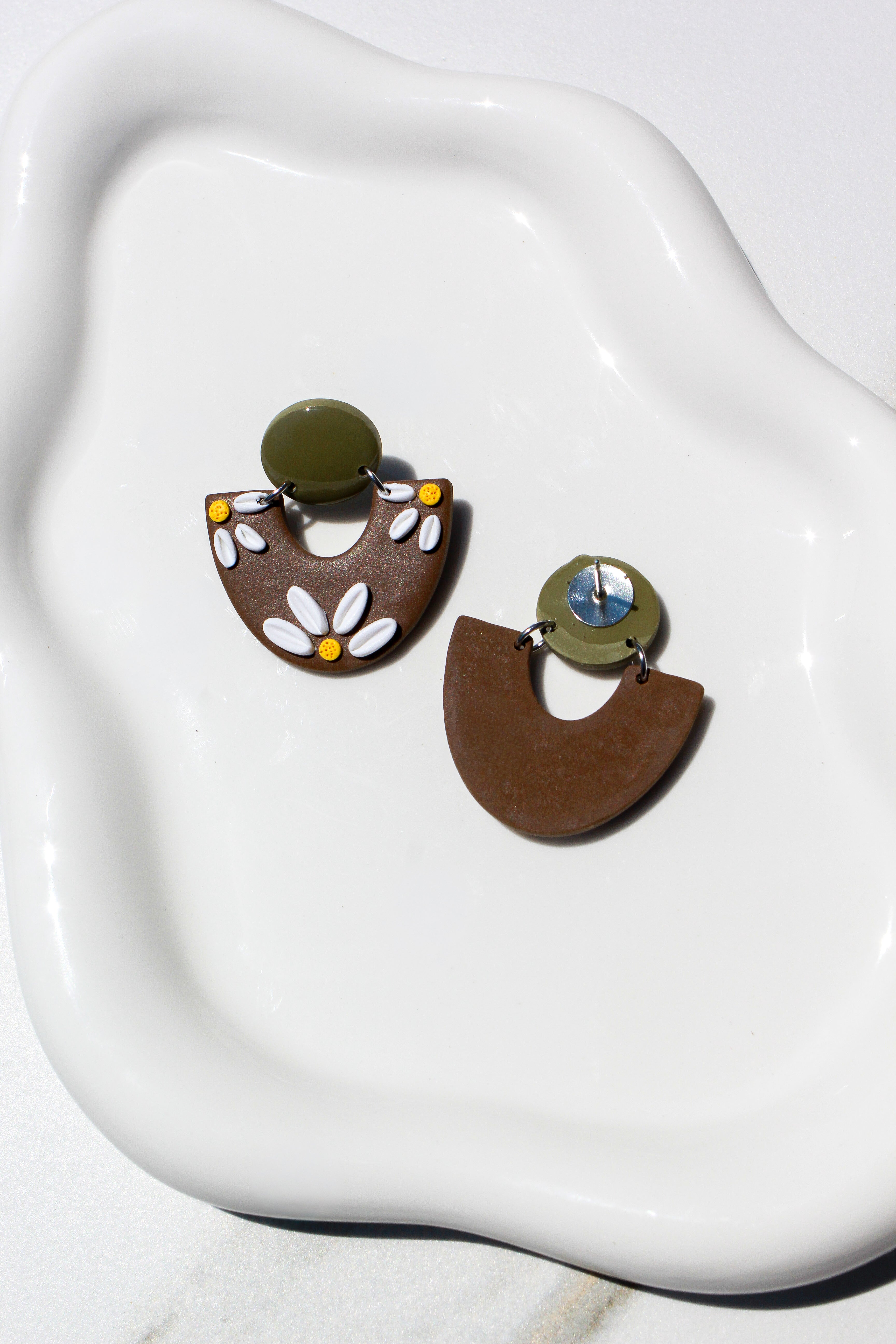 Pair of floral earrings on a white dish