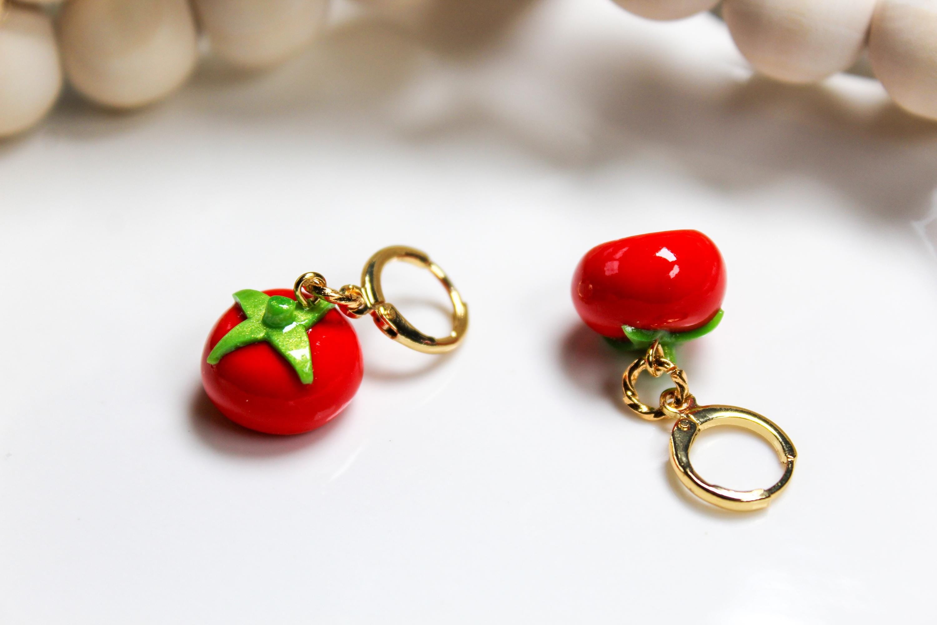 Red tomato-shaped earrings with gold hooks on a light background