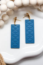 Blue textured earrings with gold hooks on a white surface with beads