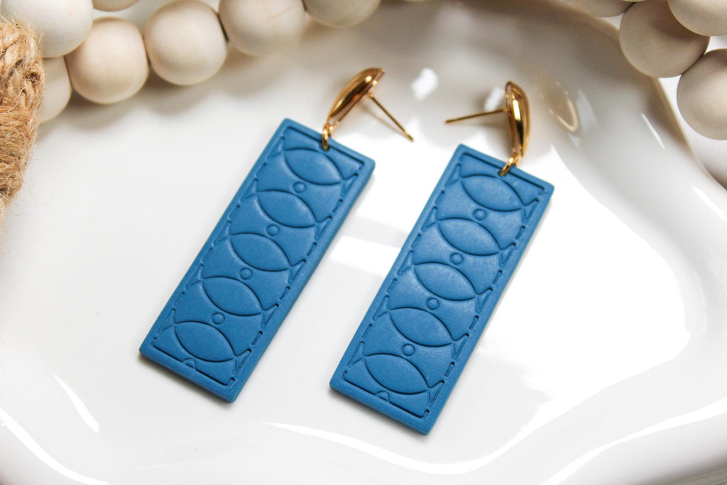 Blue textured earrings with gold hooks on a white surface with beads