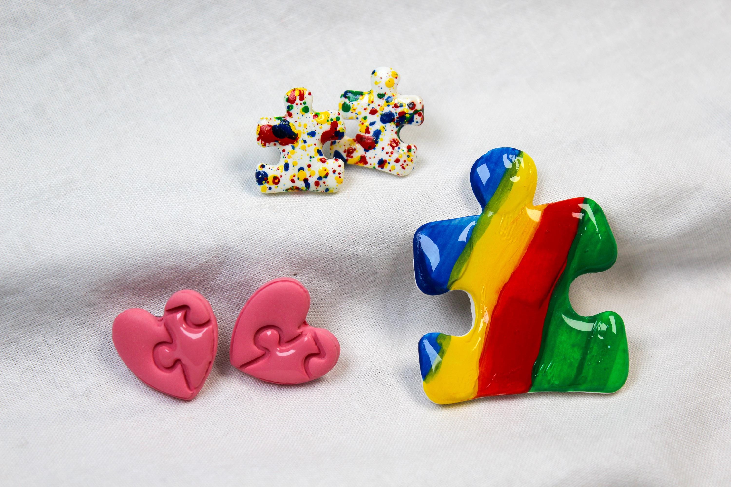 Colorful puzzle piece-shaped earrings on a light fabric background