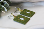 Green rectangular earrings with white snowman design on a light background