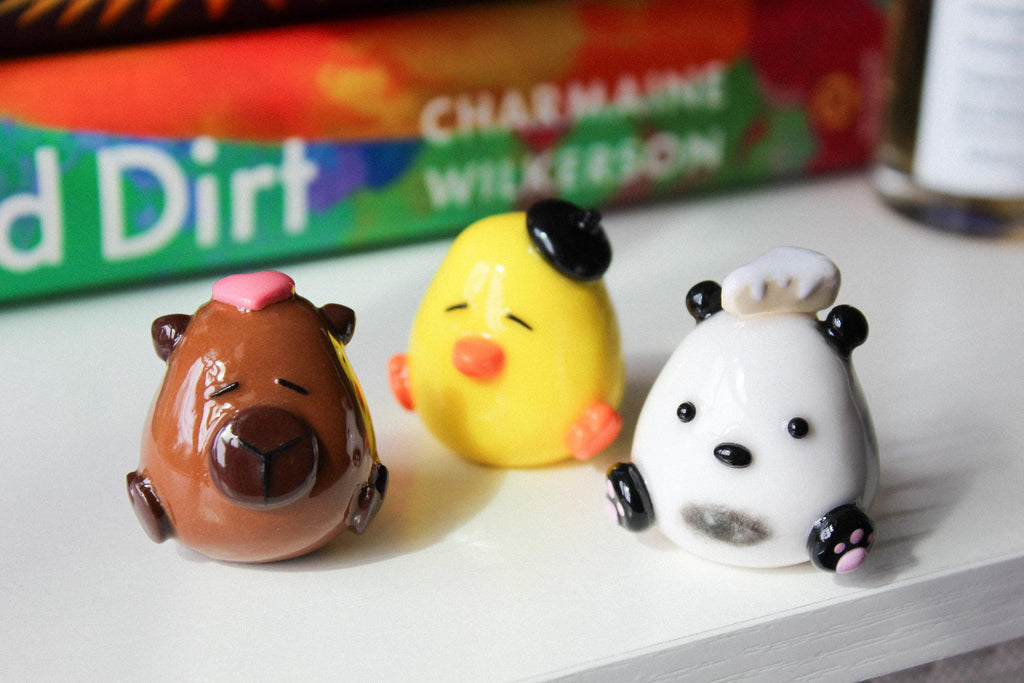 Three small animal figurines on a white surface with a book called "Good Dirt" in the background.