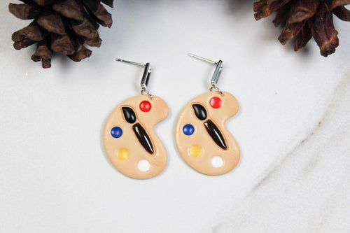 Pastry palette-shaped earrings with colorful dots on a white background