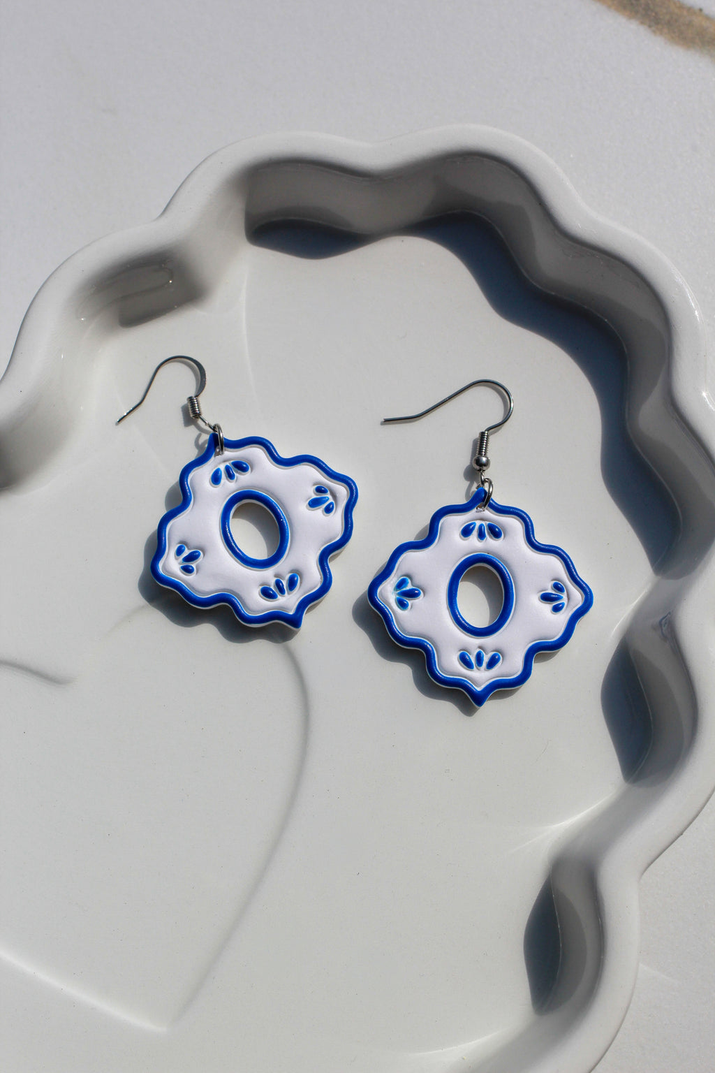 Pair of blue and white floral earrings on a textured white surface