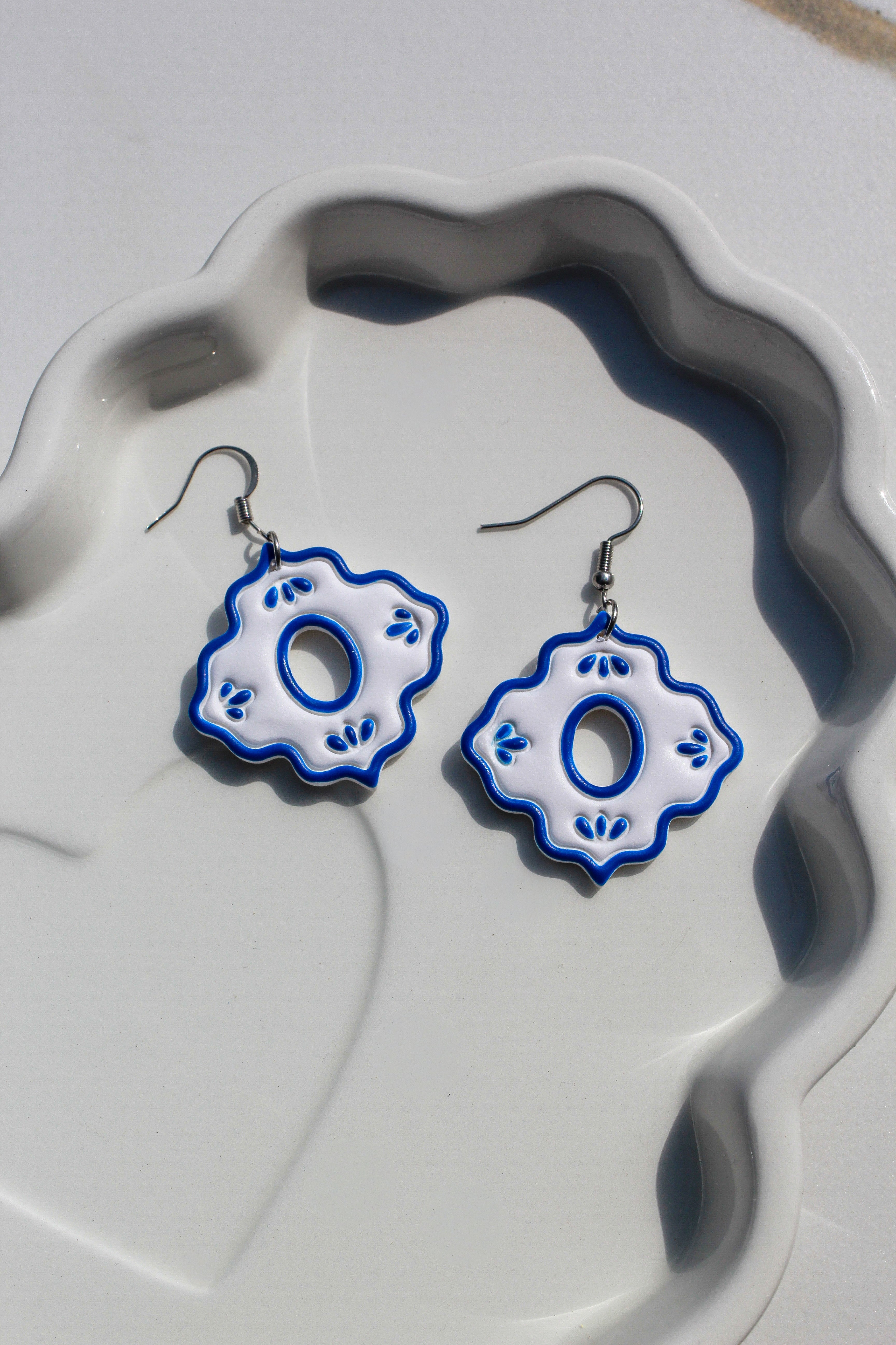 Pair of blue and white floral earrings on a textured white surface