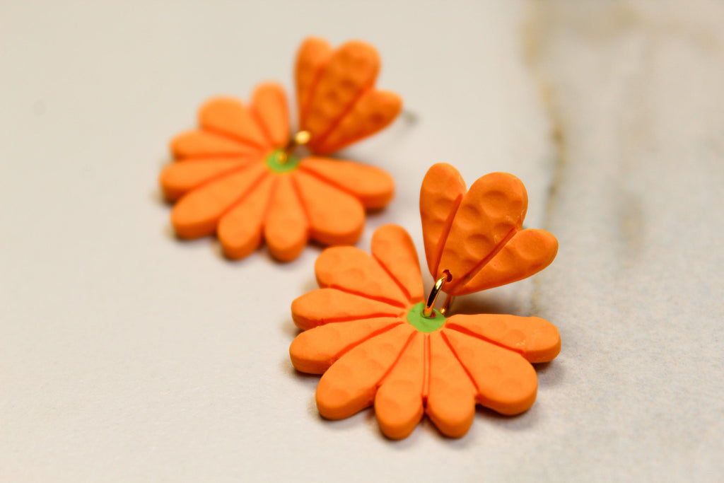 Orange flower-shaped earrings on a light background