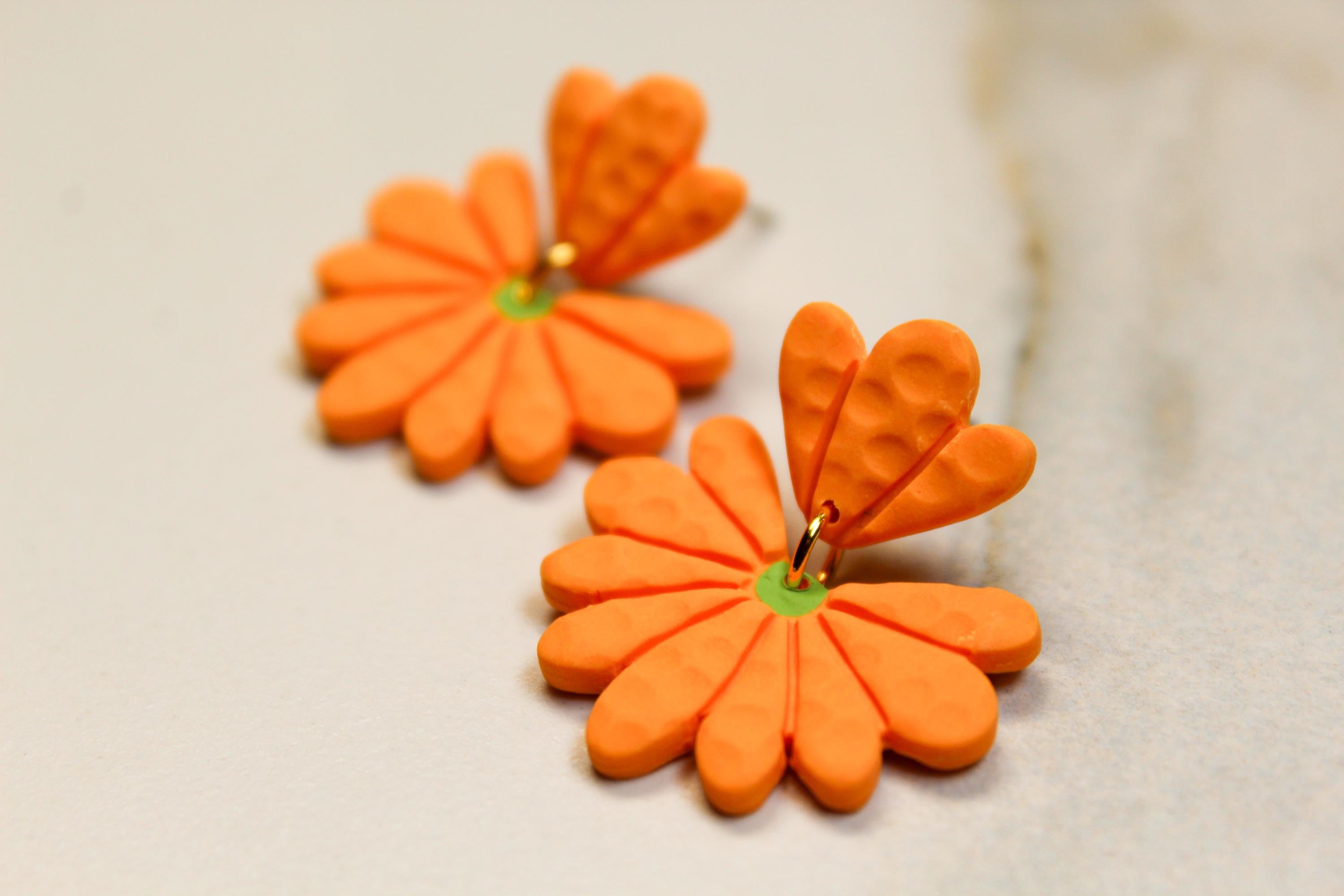 Orange flower-shaped earrings on a light background
