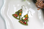 Pair of green Christmas tree-shaped earrings on a white dish