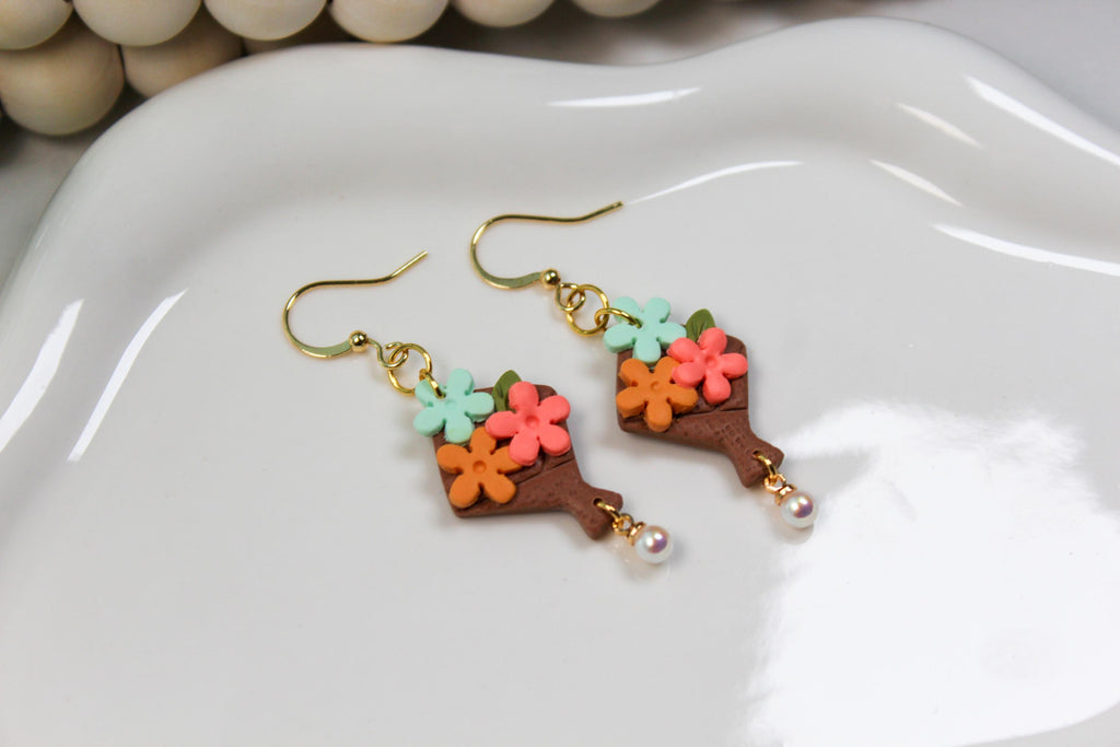 Colorful flower-shaped bouquet earrings on a white dish