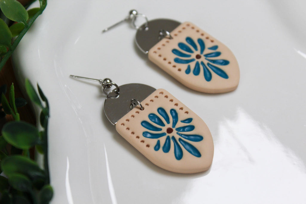 Pair of earrings with blue floral design on a white surface