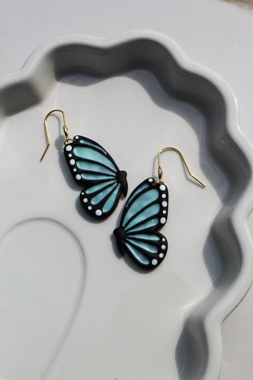 Butterfly-shaped earrings on a decorative white plate