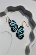 Butterfly-shaped earrings on a decorative white plate