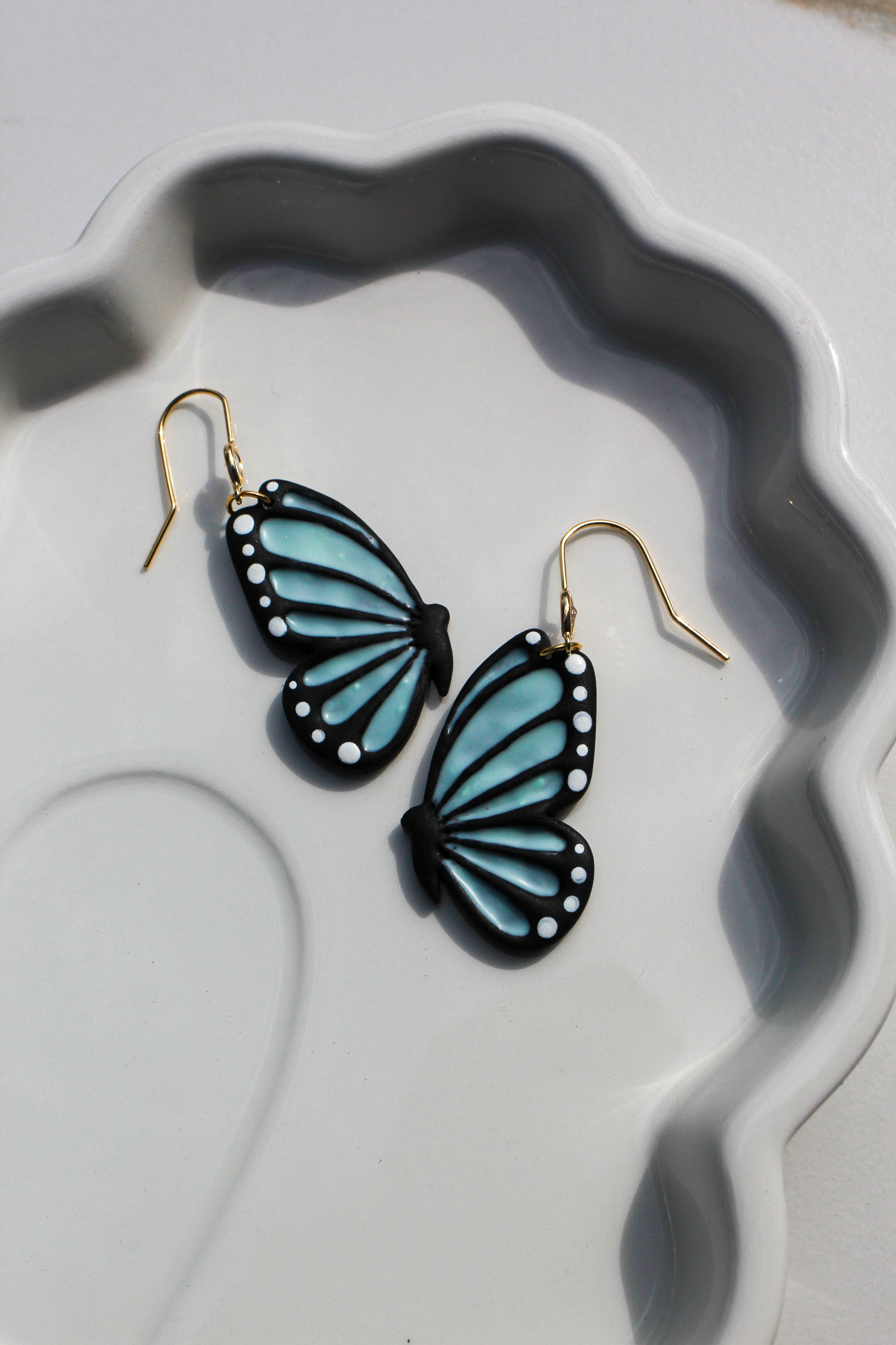 Butterfly-shaped earrings on a decorative white plate