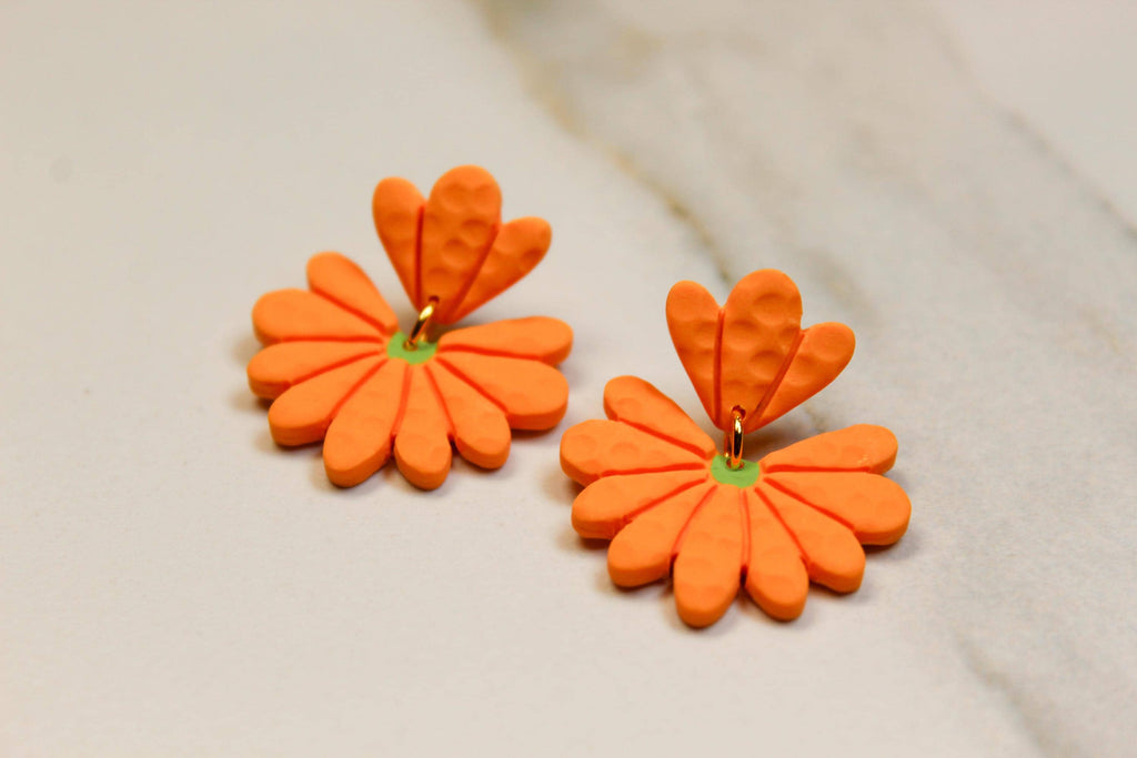 Orange flower-shaped earrings on a light beige background