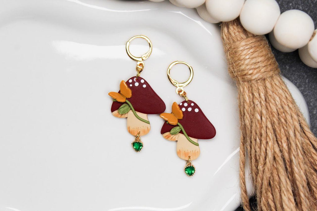 Pair of mushroom-shaped earrings on a white plate with decorative elements.